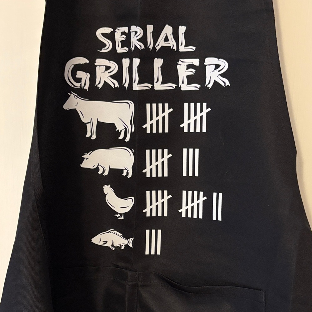 Apron Black 'Serial Griller' front pockets with adjustable neck straps. Ties